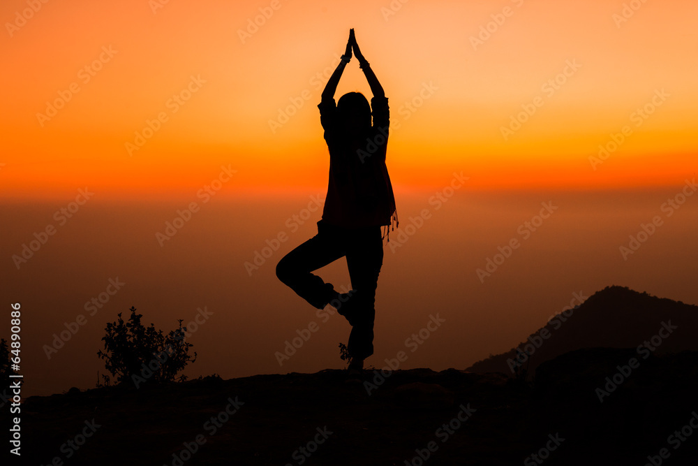Silhouette of person standing on one leg and meditating