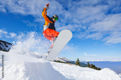 Jumping snowboarder from hill in winter