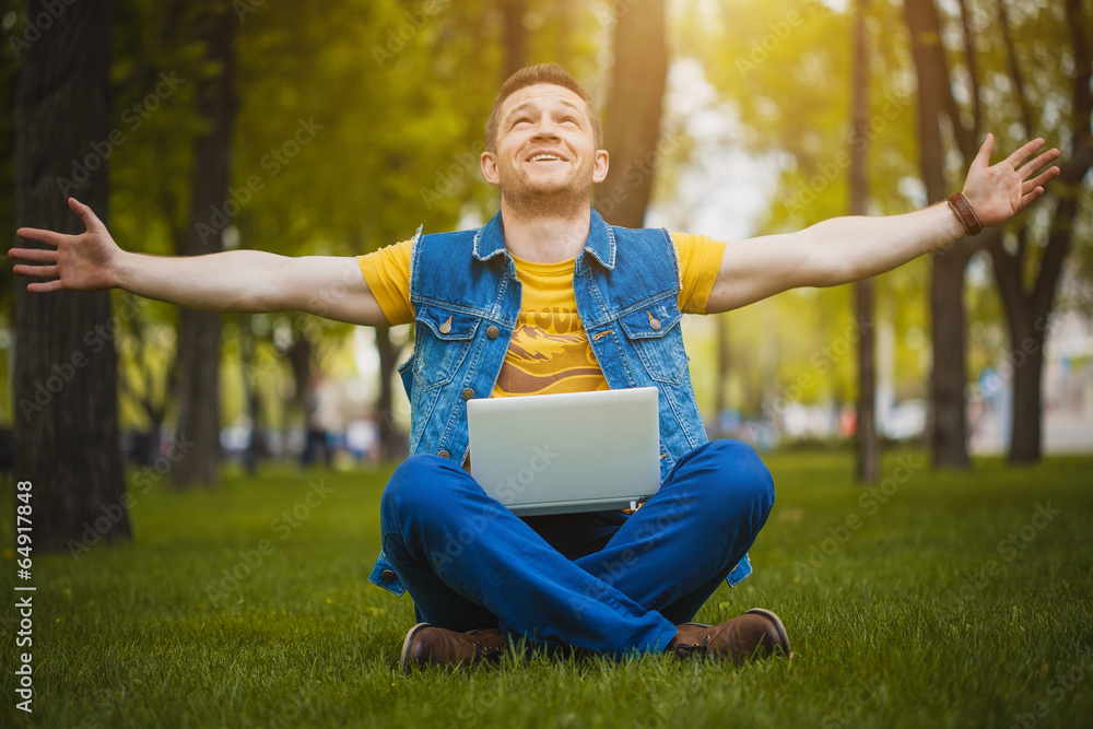 Fototapeta premium young man in the park lying on grass with laptop