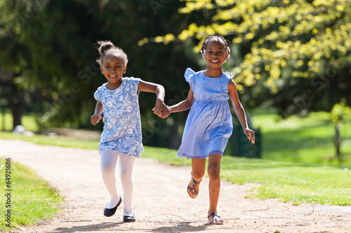 Outdoor portrait of a cute young black sisters running - Africa