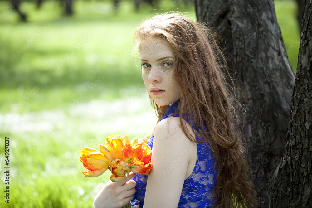 Fototapeta premium Young girl in a blue dress relaxing in spring park