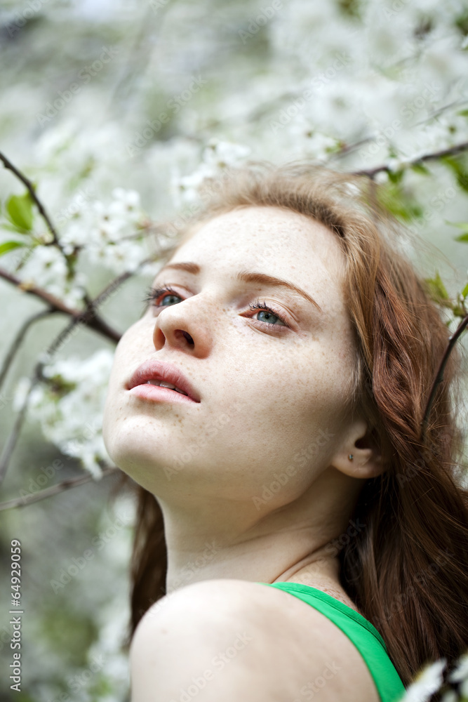 Beautiful young girl standing near blooming trees in spring gard Beautiful young girl standing near blooming trees in spring gard