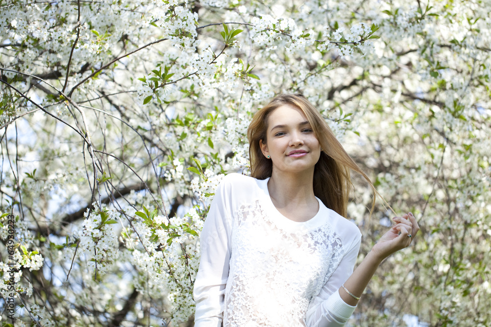 Beautiful young girl standing near blooming trees in spring gard Beautiful young girl standing near blooming trees in spring gard