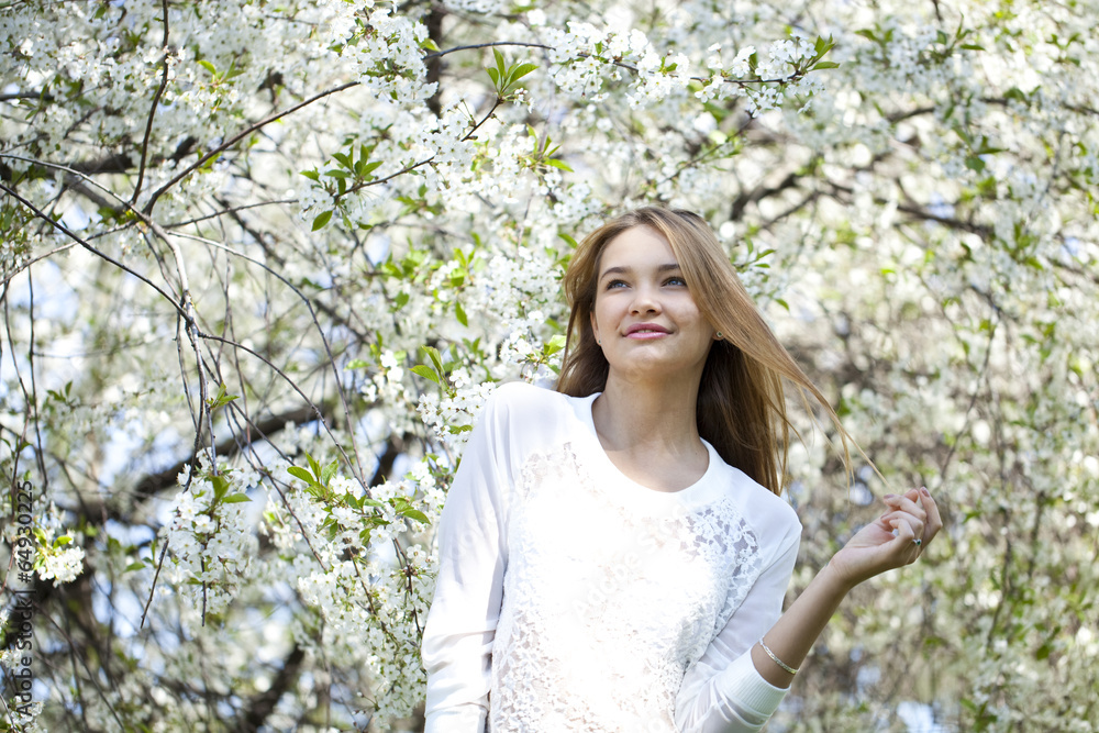 Beautiful young girl standing near blooming trees in spring gard Beautiful young girl standing near blooming trees in spring gard