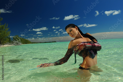 Young brunette standing at shallow tropical ocean