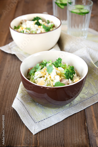 Rice dish with broccoli, meat and eggs on old wooden table