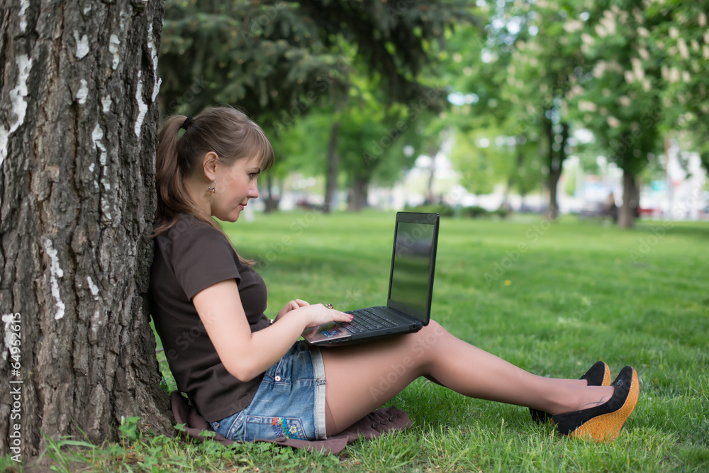 Mixed race college student lying down on the grass working Mixed race college student lying down on the grass working