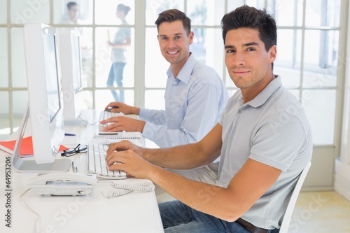 Casual businessmen smiling at camera at desk