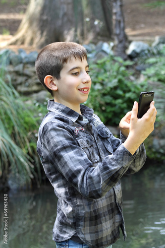 Young boy digiting a text message with a mobile phone photo