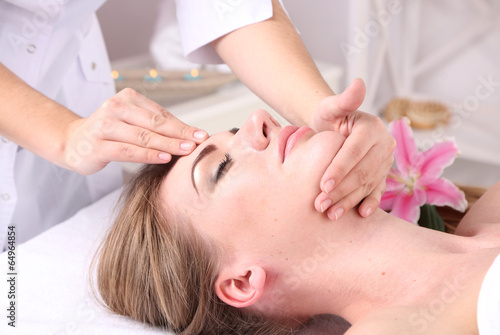 Beautiful young woman having head massage in spa salon,