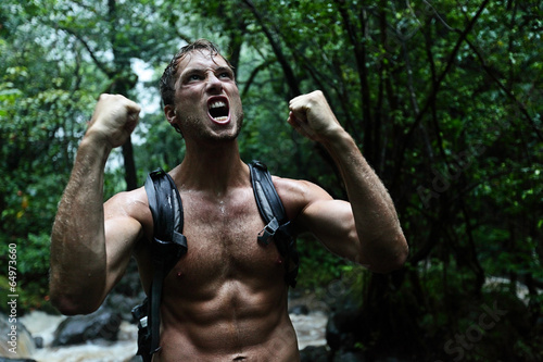 Muscular survivor man in jungle rainforest