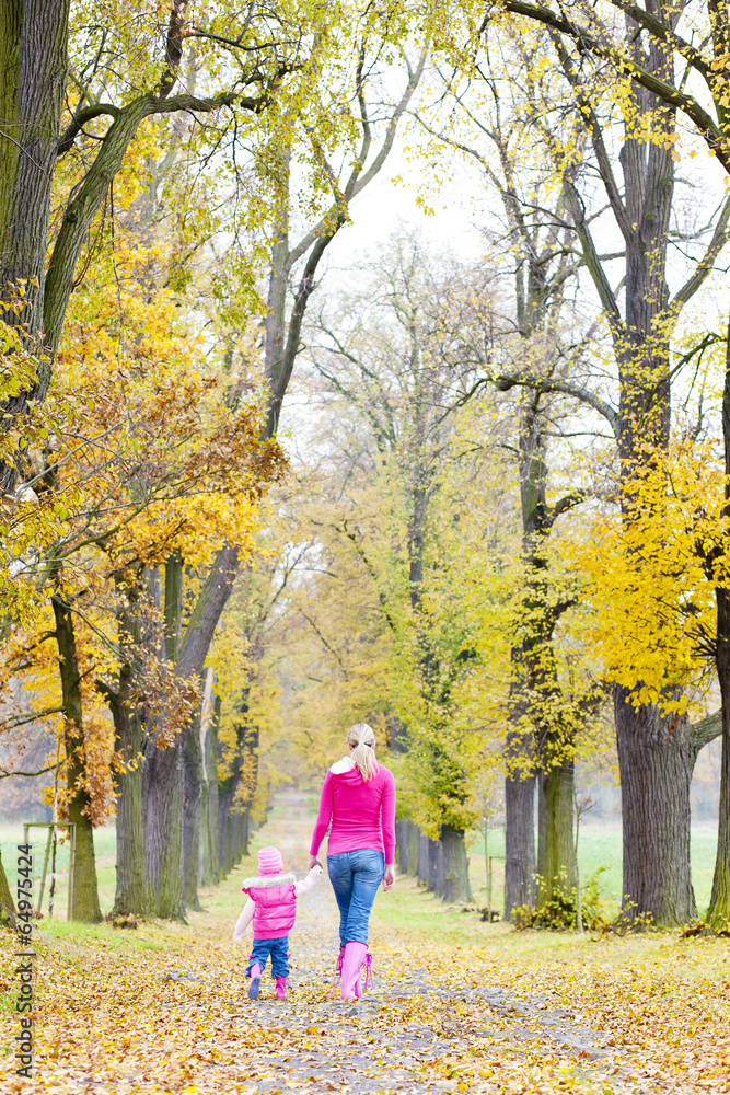 mother with her daughter in autumnal alley