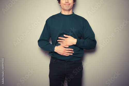 Fotografie Young man rubbing his stomach