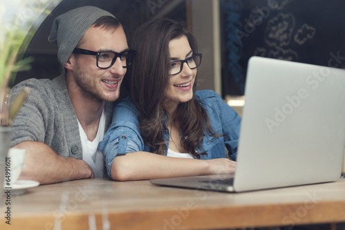 Stylish couple with contemporary laptop in cafe