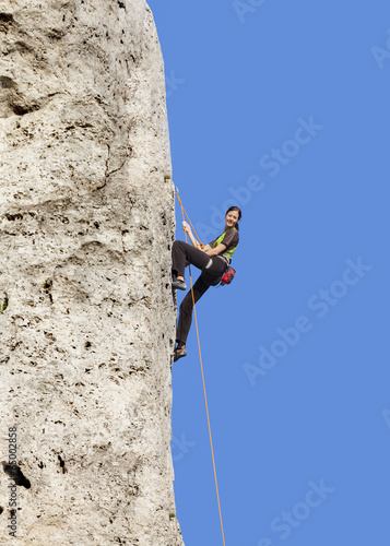 Happy woman climbing rock, active holidays.