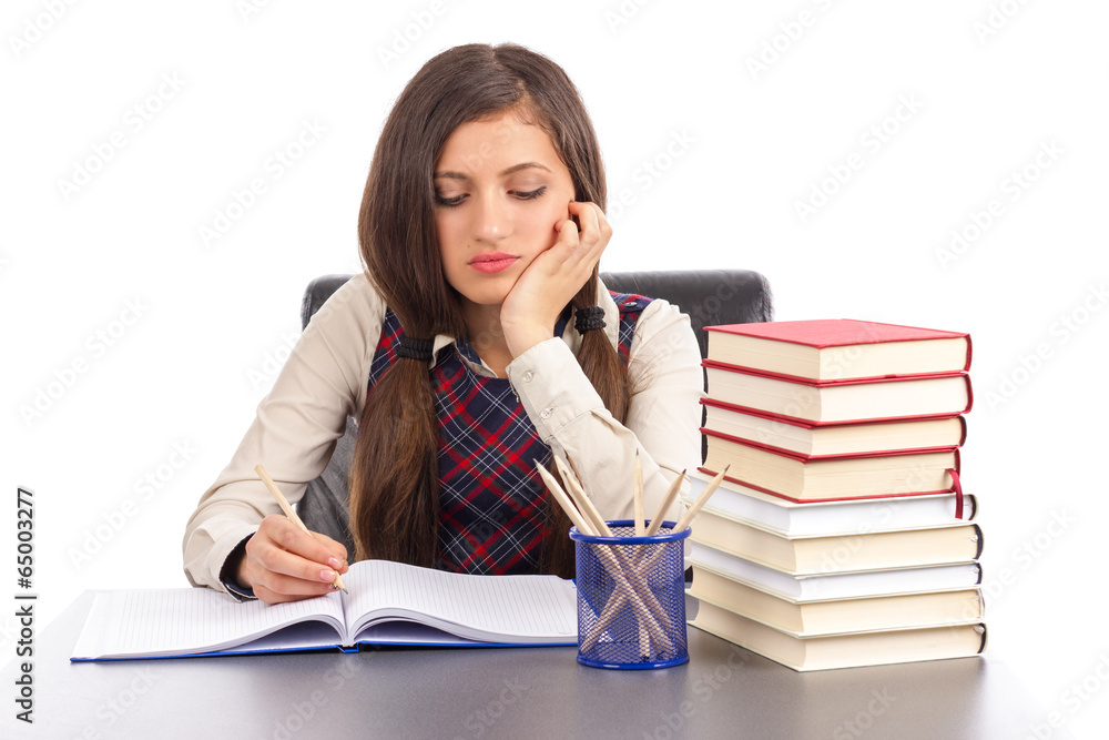 Portrait of  bored schoolgirl doing his homework at desk