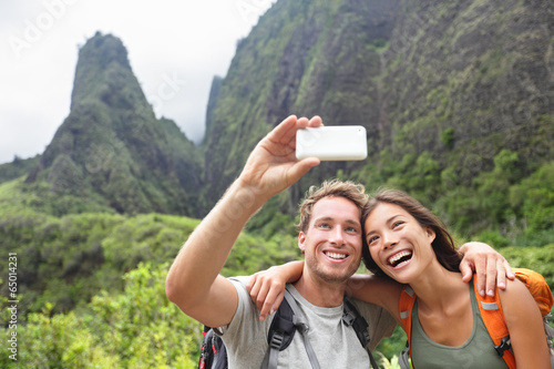 Couple taking selfie with smartphone hiking Hawaii