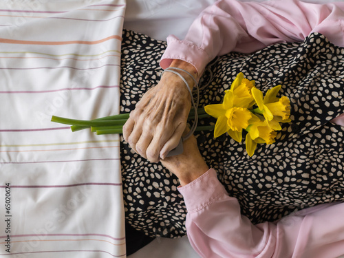 Dead womans crossed hands holding flowers