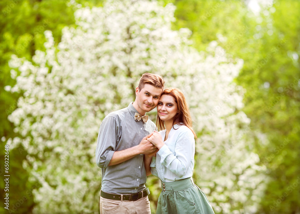 couple in love in blooming apple trees garden, smiling couple in love in blooming apple trees garden, smiling