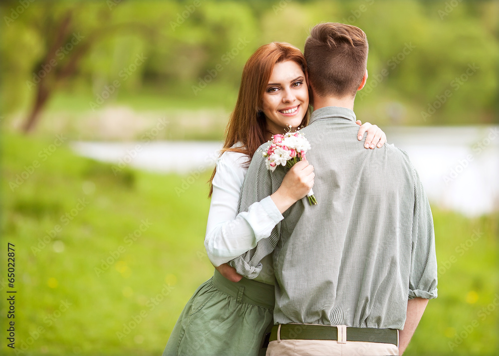 Obraz premium young happy couple sitting on river at sunset