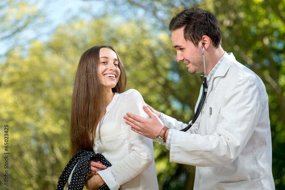 Young doctor listnening with stethoscope to the woman Young doctor listnening with stethoscope to the woman