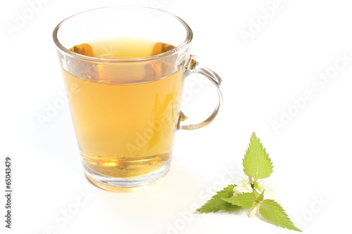 Fresh nettle with white flowers and cup of beverage