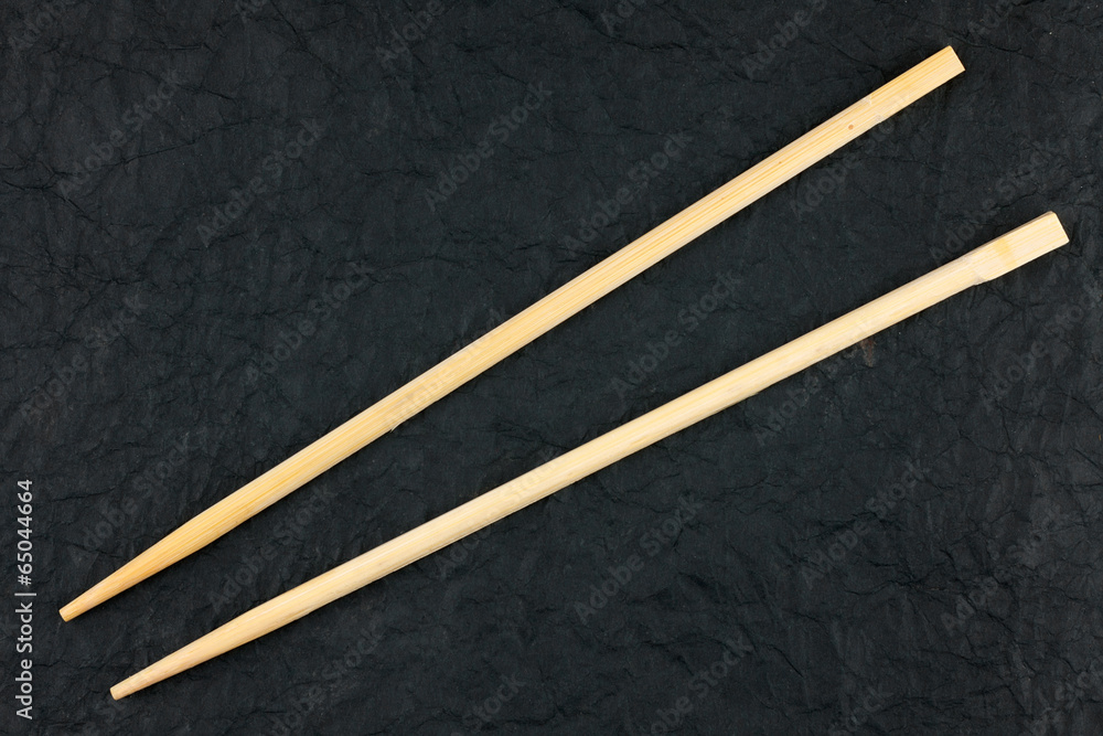 Chopsticks lay on a black napkin Chopsticks lay on a black napkin
