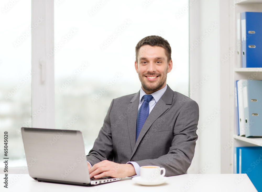 smiling businessman with laptop and coffee