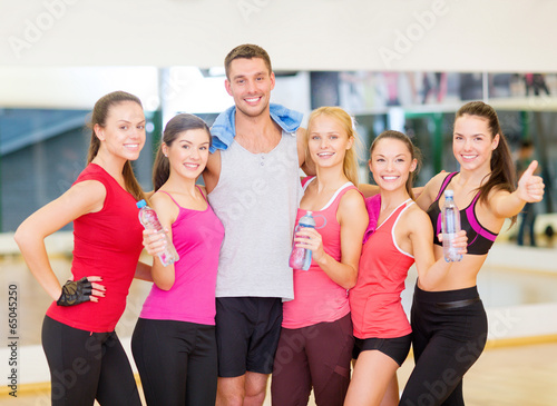 group of happy people in gym with water bottles