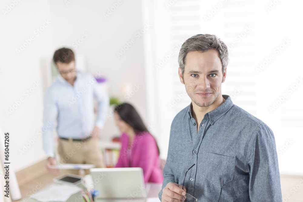 senior businessman standing in front of his colleagues in office senior businessman standing in front of his colleagues in office