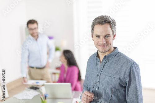 senior businessman standing in front of his colleagues in office © jackfrog