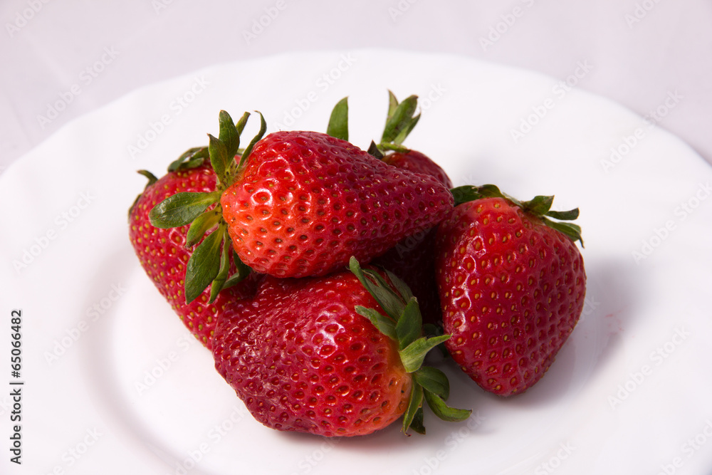 ripe red strawberries with leaves on a plate ripe red strawberries with leaves on a plate