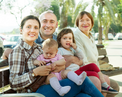 portrait of happy multigeneration family sitting on bench