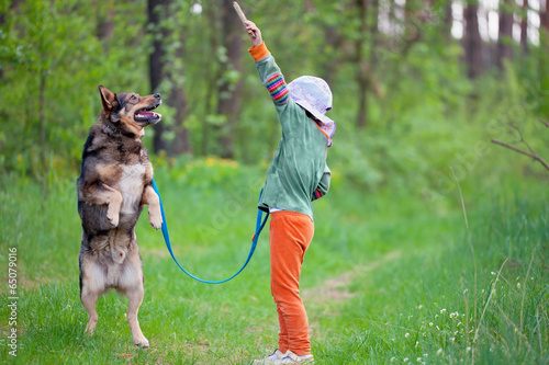 Little girl schooling dog in the forest