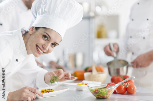 closeup on a  female chef preparing a dish her team in the backg photo