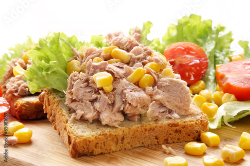 Sandwich with tuna and corn on wood background