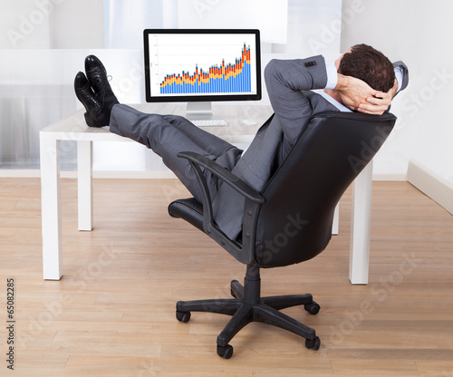 Businessman With Feetup Relaxing At Computer Desk photo