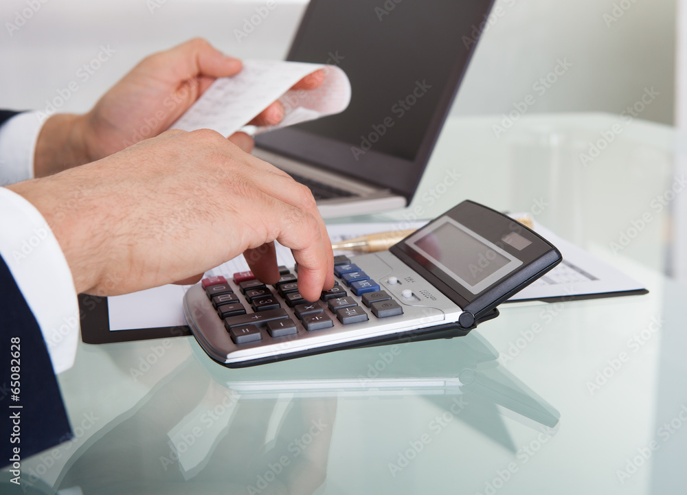 Businessman Calculating Expense In Office Businessman Calculating Expense In Office