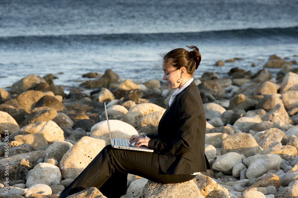 attractive business woman working on laptop at beach