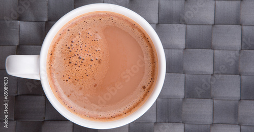 A mug of hot chocolate on a woven place mat.