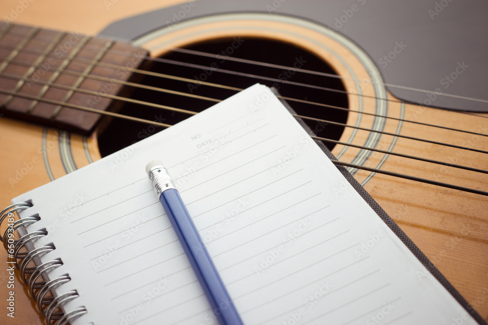 Naklejka premium Notebook and pencil on guitar