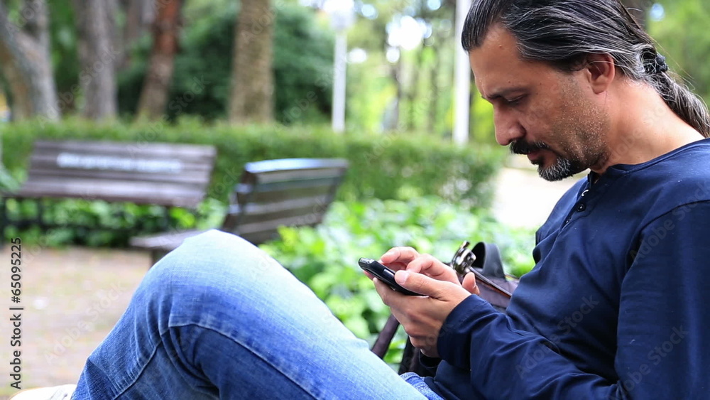 Man Using a Smartphone in park Man Using a Smartphone in park