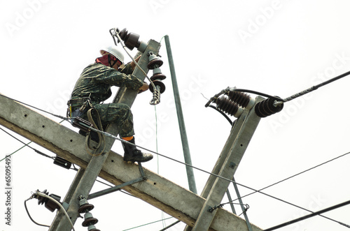 Electrician lineman repairman worker at climbing work on electri photo