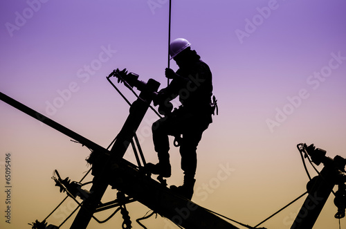 Electrician lineman repairman worker at climbing work on electri photo