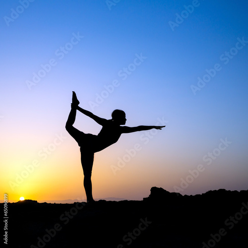 Woman doing yoga sunset silhouette