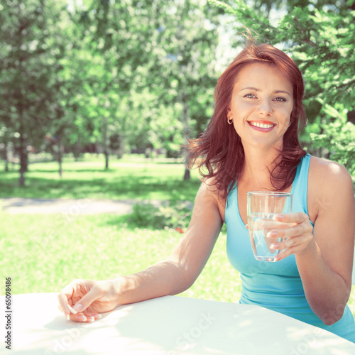 Portrait of young beautiful woman drinking water on picnic