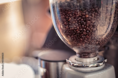 Coffee grinder and Barista prepares espresso in coffee shop photo