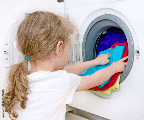 Little girl doing laundry. Housework concept. photo