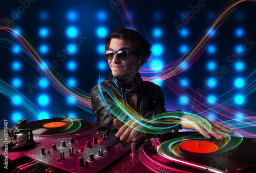 Young Dj mixing records with colorful lights photo