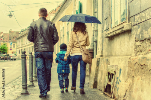 Mother, father and child walking together on a rainy day